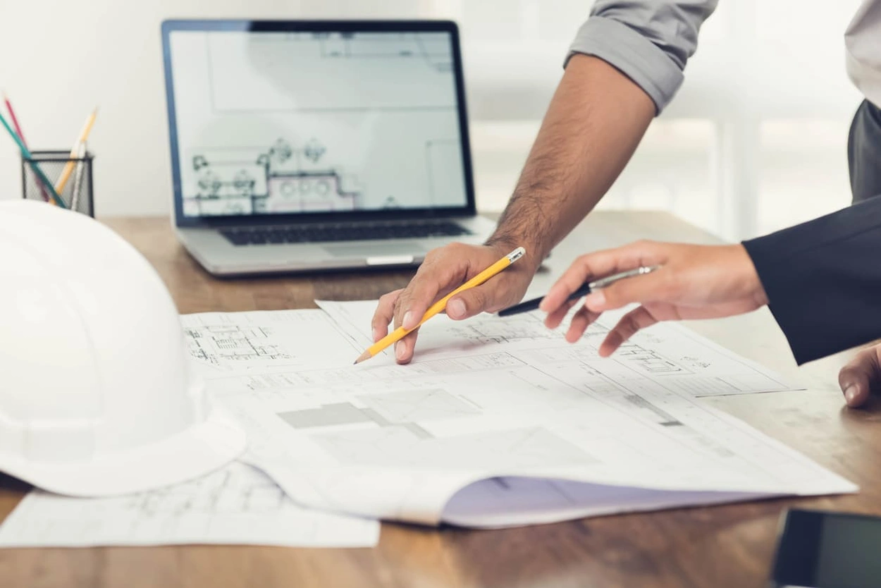 Architects using both a digital floor plan and a printed blueprint for a project