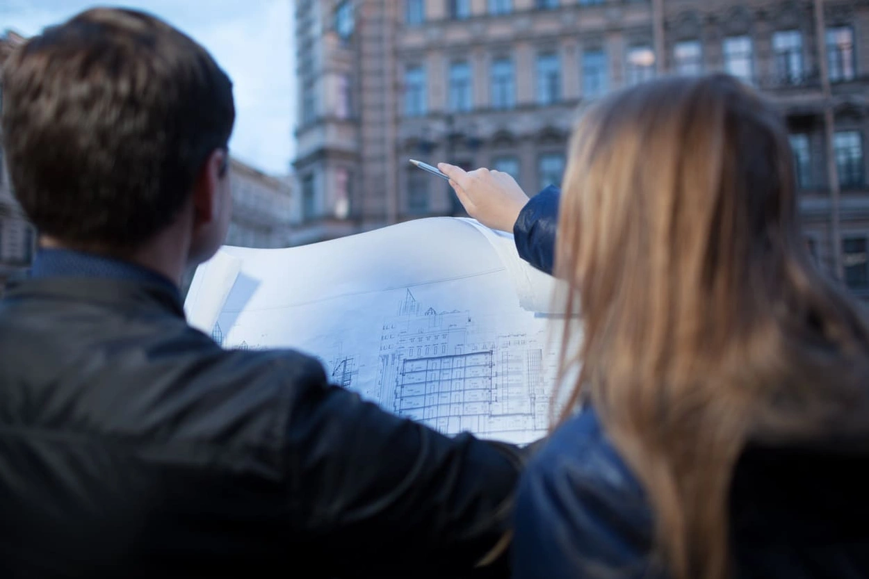 People looking at a detailed blueprint of an old building