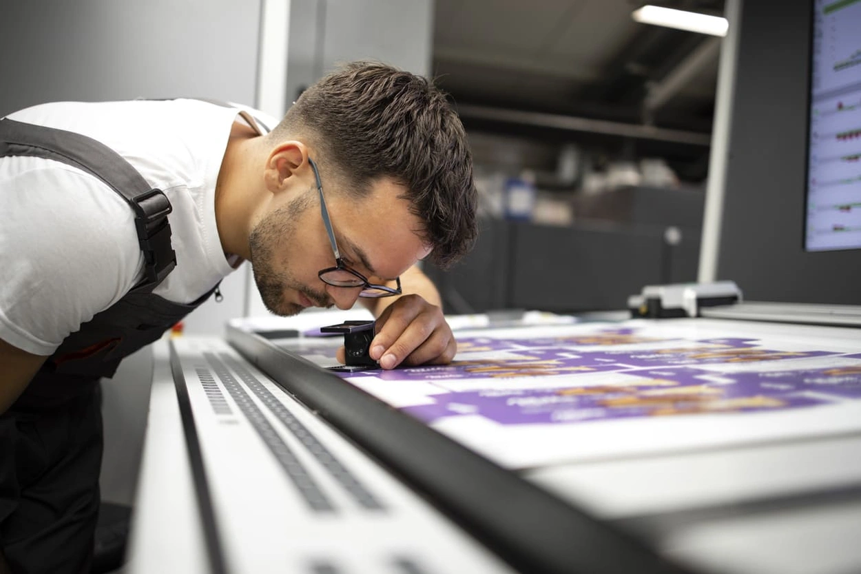 Print shop manager assessing print quality after taking steps to reduce printer ink cost