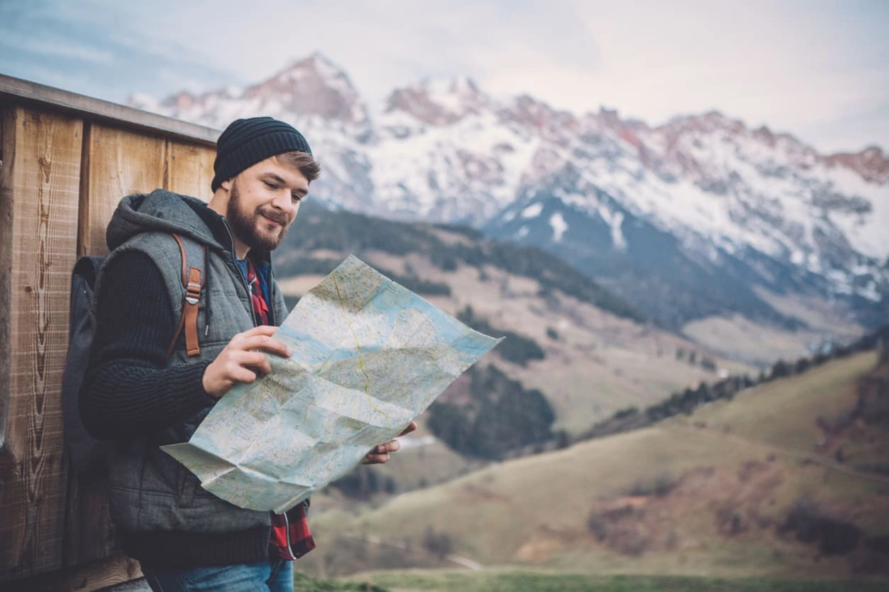 Adventurer holding a large format map with mountains in the background