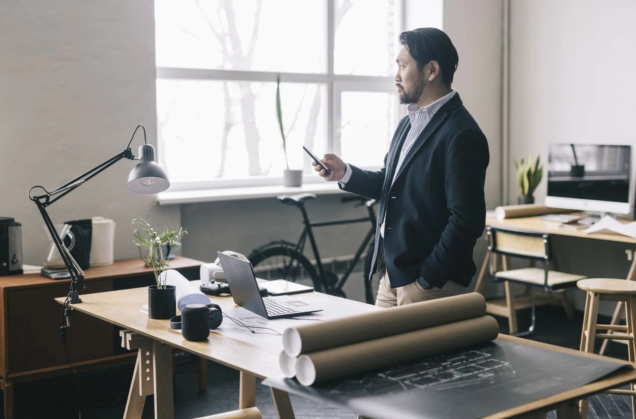 Architectural director using his smartphone to print out large format printers with new large format printers in the office