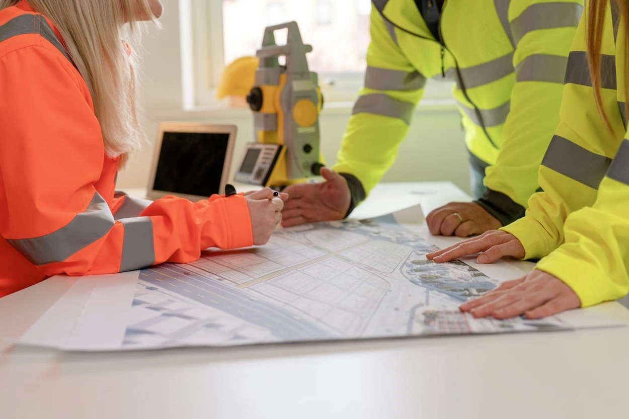 Workers using blueprints and GIS for civil engineering meetings