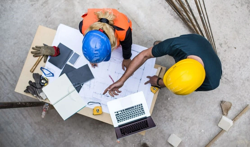 Construction workers securely accessing new blueprints with on-site connectivity and solid cybersecurity in construction